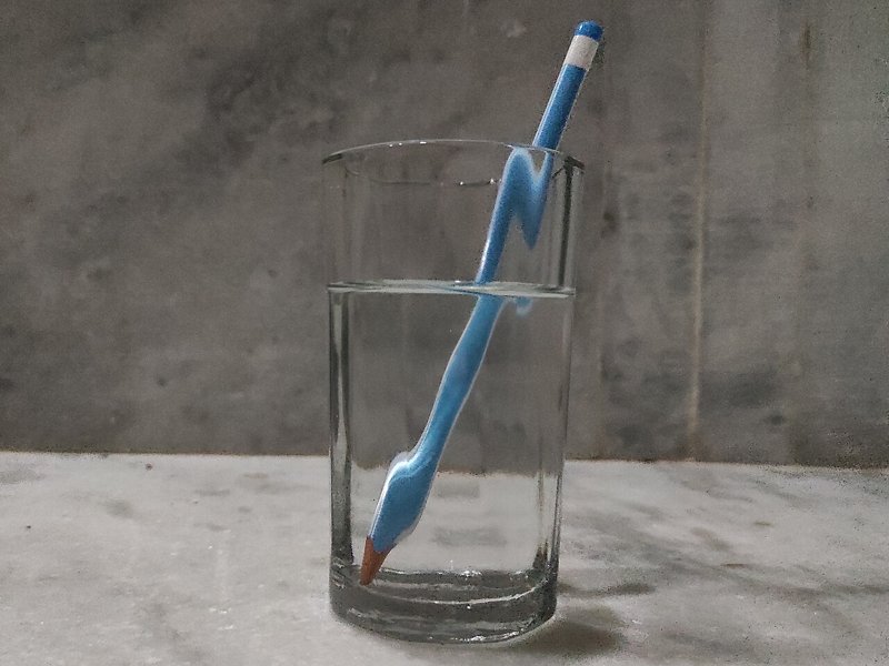 Ein Bleistift in einem Wasserglas scheint an der Wasseroberfläche geknickt